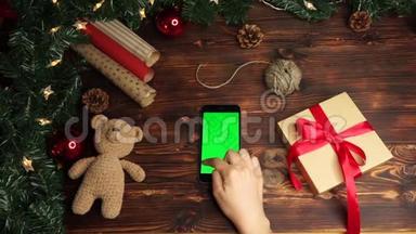 木制背景。 上景。 黑色智能手机，绿色屏幕躺在桌子上，上面假日装饰。